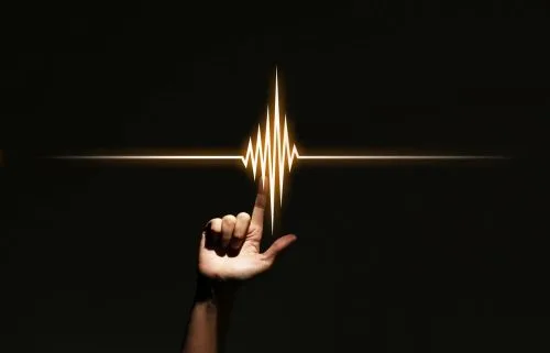 Black background with a hand in the shape of an L, touching a set of golden frequency cords.